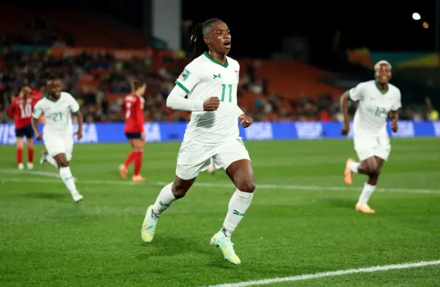 Barbara Banda wheels away to celebrate, with her teammates chasing her.