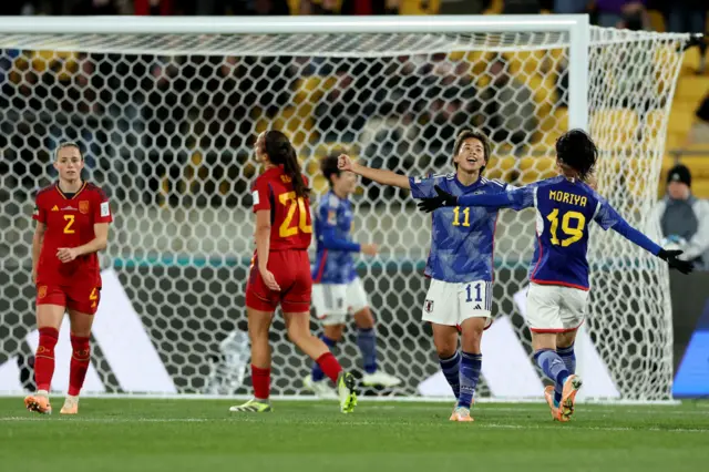 Tanaka holds her hands high in the air after adding a fourth for Japan.