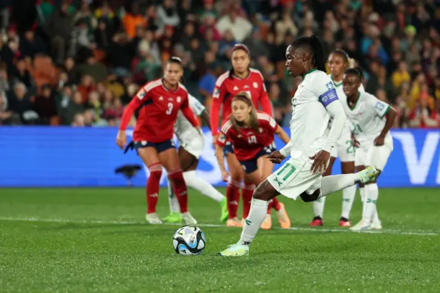 Barbara banda shoots from the penalty spot with players from both sides watching on.