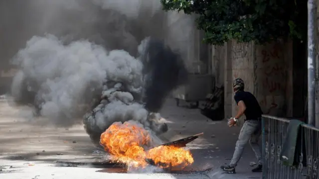 A Palestinian man throws stones during clashes over an Israeli military operation in Jenin