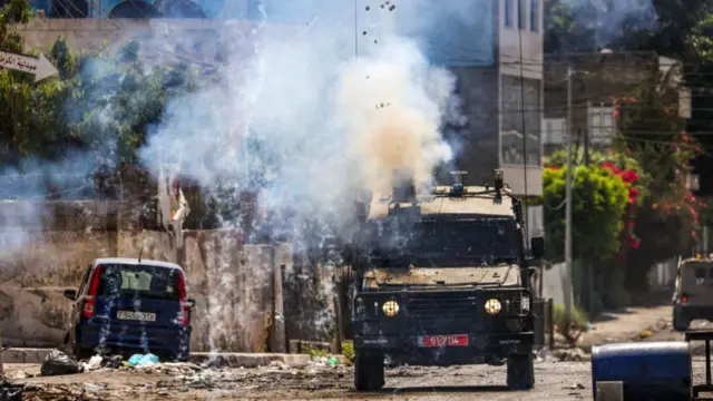 Israeli soldiers fire tear gas cannisters from an armoured vehicle