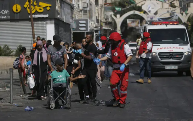 Members of Palestine Red Crescent Society (PRCS) help refugees to evacuate Jenin Camp