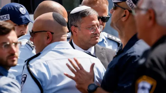 Itamar Ben-Gvir is surrounded by police as he walks around the site of the attack