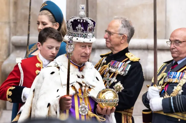 The King leaves Westminster Abbey wearing the Imperial State Crown and carrying the Sovereign's Orb and Sceptre