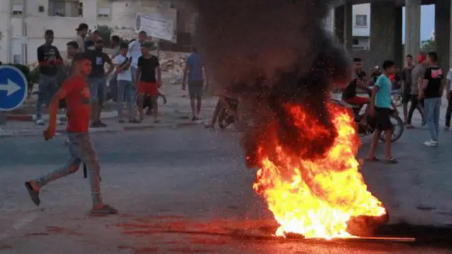 Tunisian youths block the road to migrants by setting tyres on fire as tensions rose in Sfax after the burial of a young Tunisian stabbed to death during a scuffle between residents and migrants from sub-Saharan Africa - 4 July 2023