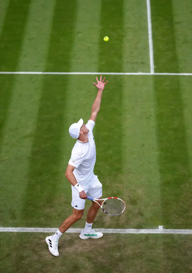 Jan Choinski throwing the ball in the air as he prepares to serve