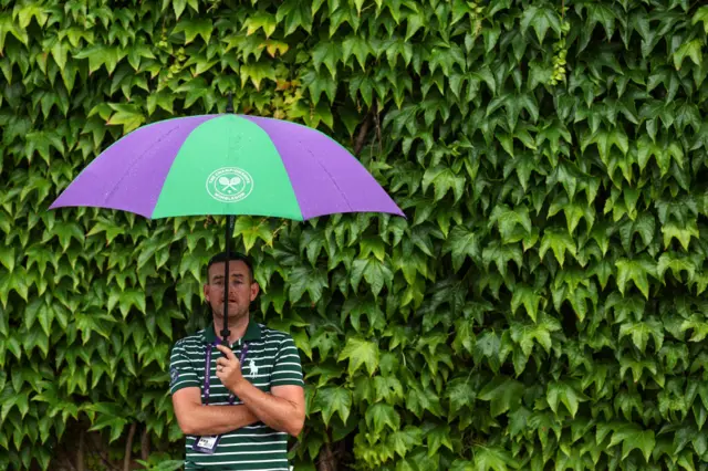 A groundskeeper stands in the rain