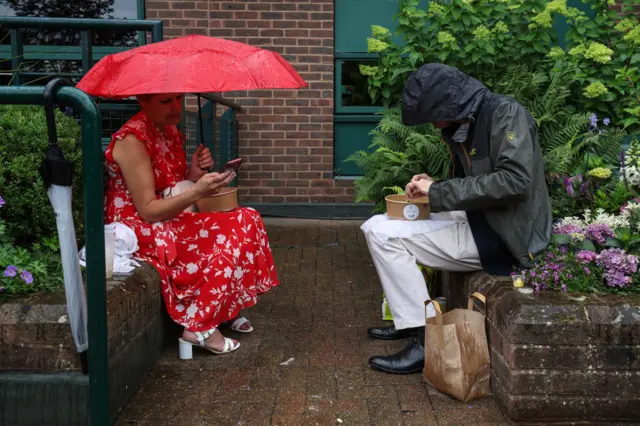 Spectators eat their lunch in the rain