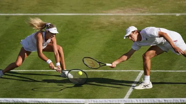 Katie Boulter and Alex de Minaur go for a ball at the net