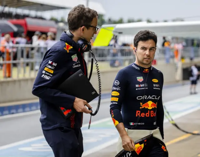 Sergio Perez walks with a red Bull crew member