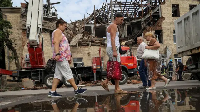 Local residents walk near a building damaged by a Russian drone strike, amid Russia's attack on Ukraine, in Kharkiv, Ukraine August 1, 2023.