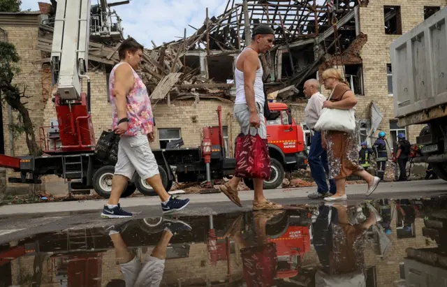 Local residents walk near a building damaged by a Russian drone strike, amid Russia's attack on Ukraine, in Kharkiv.