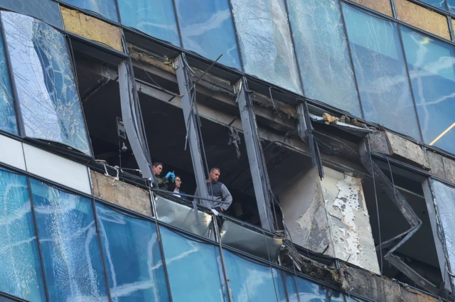 Men investigate a damaged building