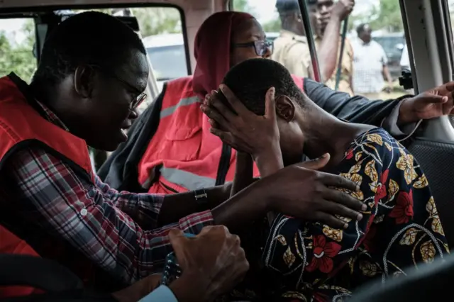 A member of the Kenyan Red Cross comforts a rescued follower of the the Good News International Church, believed to be practising mass starvation, in Shakahola, outside the coastal town of Malindi, on April 25, 2023.