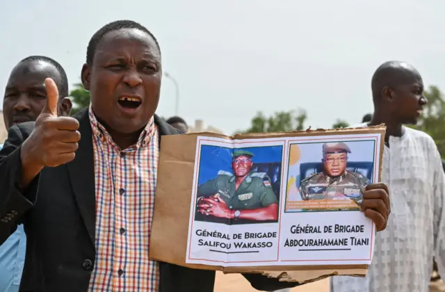 A supporter of Niger's National Council for the Safeguard of the Homeland (CNSP) holds up a placeard with a photo of General Abdourahamane Tiani on in Niamey on August 6, 2023.