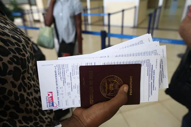 A woman holding a Mali passport.