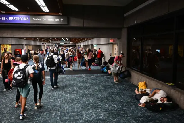 Passengers walking and sleeping in an airport corridor