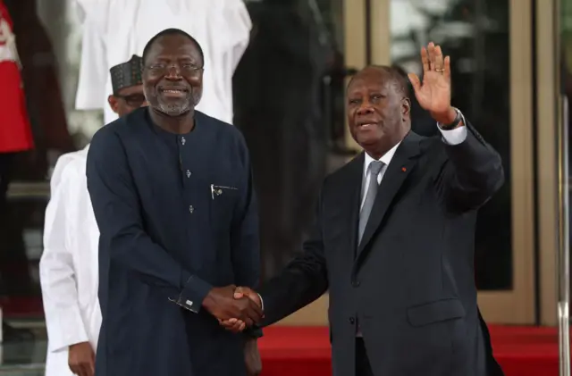 Ivory Coast President Alassane Ouattara (R) waves to the press as he is received by Ecowas President Omar Touray.