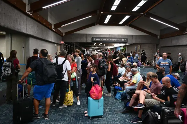 Passengers try to rest and sleep after canceled and delayed flights while others wait to board flights off the island as thousands of passengers were stranded at the Kahului Airport (OGG).