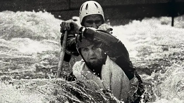 Black and white image of Jon Goodwin competing in a canoe