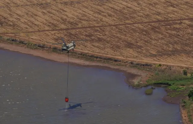 A National Guard helicopter collects seawater off the coast of Maui to help fight the wildfires