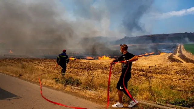 A firefighter and a volunteer try to put out a wildfire,