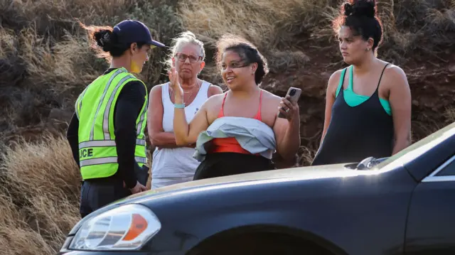 A police officer talks to people on the island of Maui