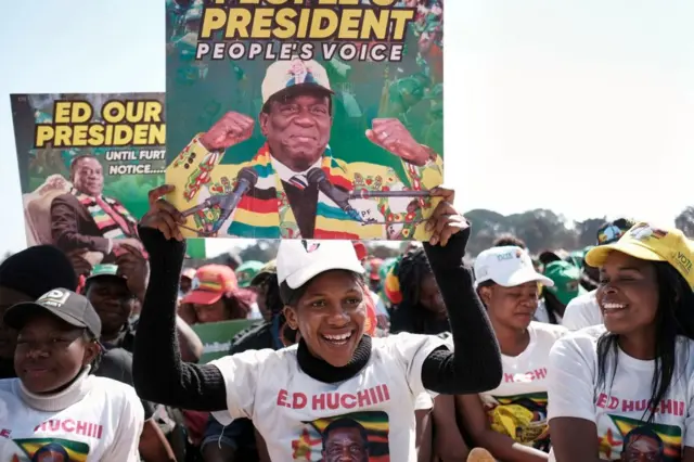 Supporters of Zimbabwe's ruling party ZANU PF hold up election campaign banners during a rally addressed by party president Emmerson Mnangagwa, in Harare on August 9, 2023.