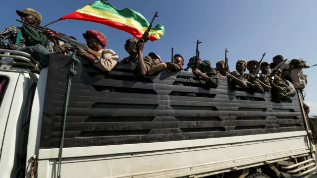 Ethiopia Tigray crisis: Members of Amhara region militias ride on their truck as they head to face the Tigray Peoples Liberation Front in Sanja