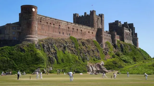 A cricket match takes place at Bamburgh Castle, Northumberland, in June