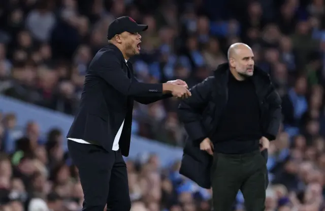 Kompany and Guardiola stand side by side on the touchline.