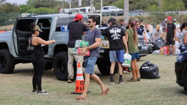 Amid a crowd of volunteers, a man carries food supplies from a truck