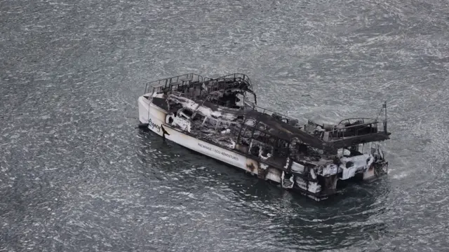 A burned out boat is seen in the waters off the shore of Lahaina town in Maui