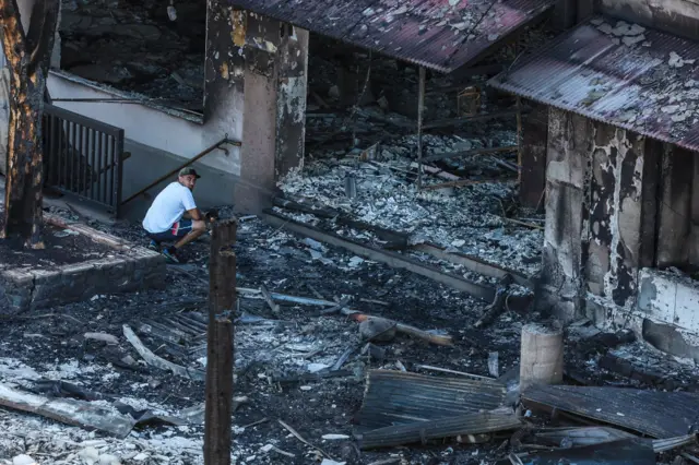 man crouches in rubble