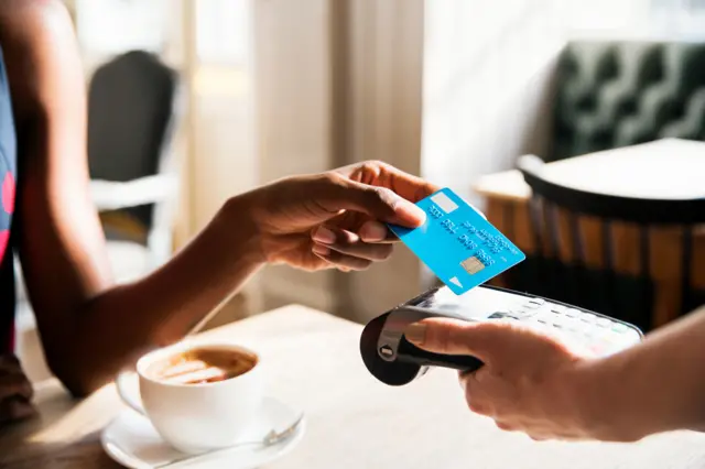 Woman paying for coffee with contactless card