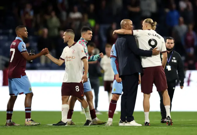 Burnley and City players embrace after full time.