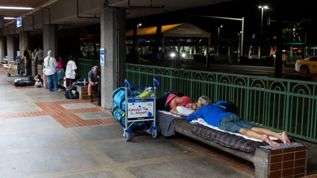 ourists who were evacuated following wild fire destruction settle for the night as they wait for a flight to leave the island of Maui at the Kahului Airport, in Kahului, Hawaii, USA.