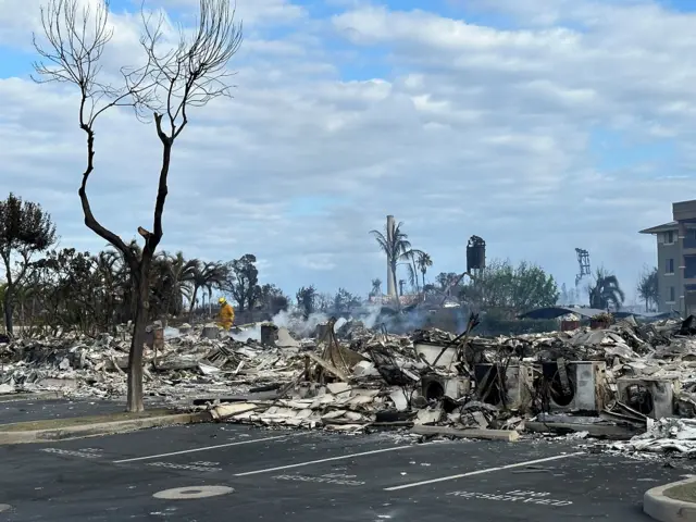 A firefighter works to put out hot spots smouldering in the rubble of an apartment complex