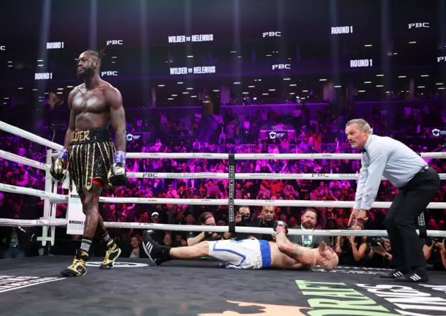 Robert Helenius lies on the floor as Deontay Wilder walks away