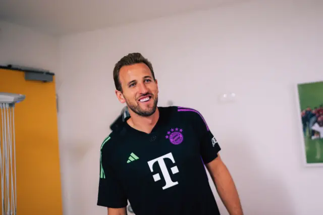 Harry Kane smiles in his new Bayer shirt as he undergoes his medical.