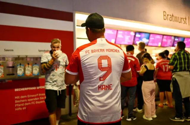 A fan waitr in the concourse for food with his Kane 9 shirt on.