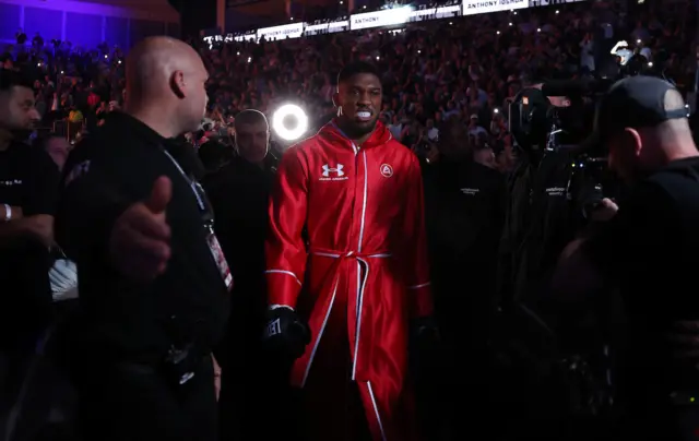 Anthony Joshua dressed in red makes his ring walk