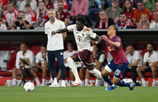 Xavi Simons challenges Alphonso Davies in midfield.