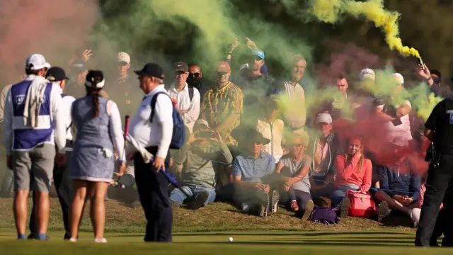 People enter 17th green with flares