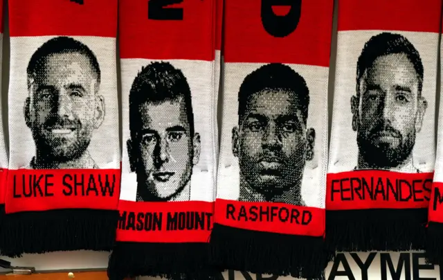 Replica scarves with players faces hang from a kiosk outside Old Trafford.