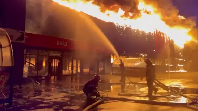 Firefighters use hose to douse flames at a shopping centre