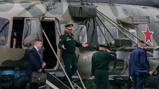 Sergei Shoigu walks down the steps of a helicopter