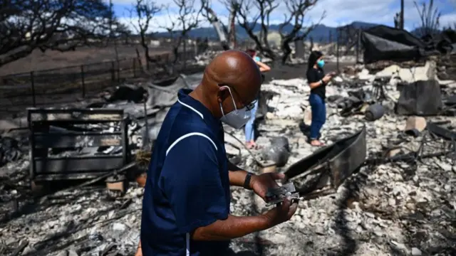 A man looks for belongings through the ashes of his family's home