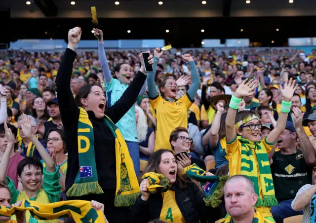 Australia fans shout and cheer for the side from the stands.