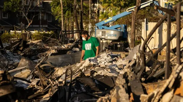 Volunteer assesses the damage of charred apartment complex in the aftermath of a wildfire in Lahaina